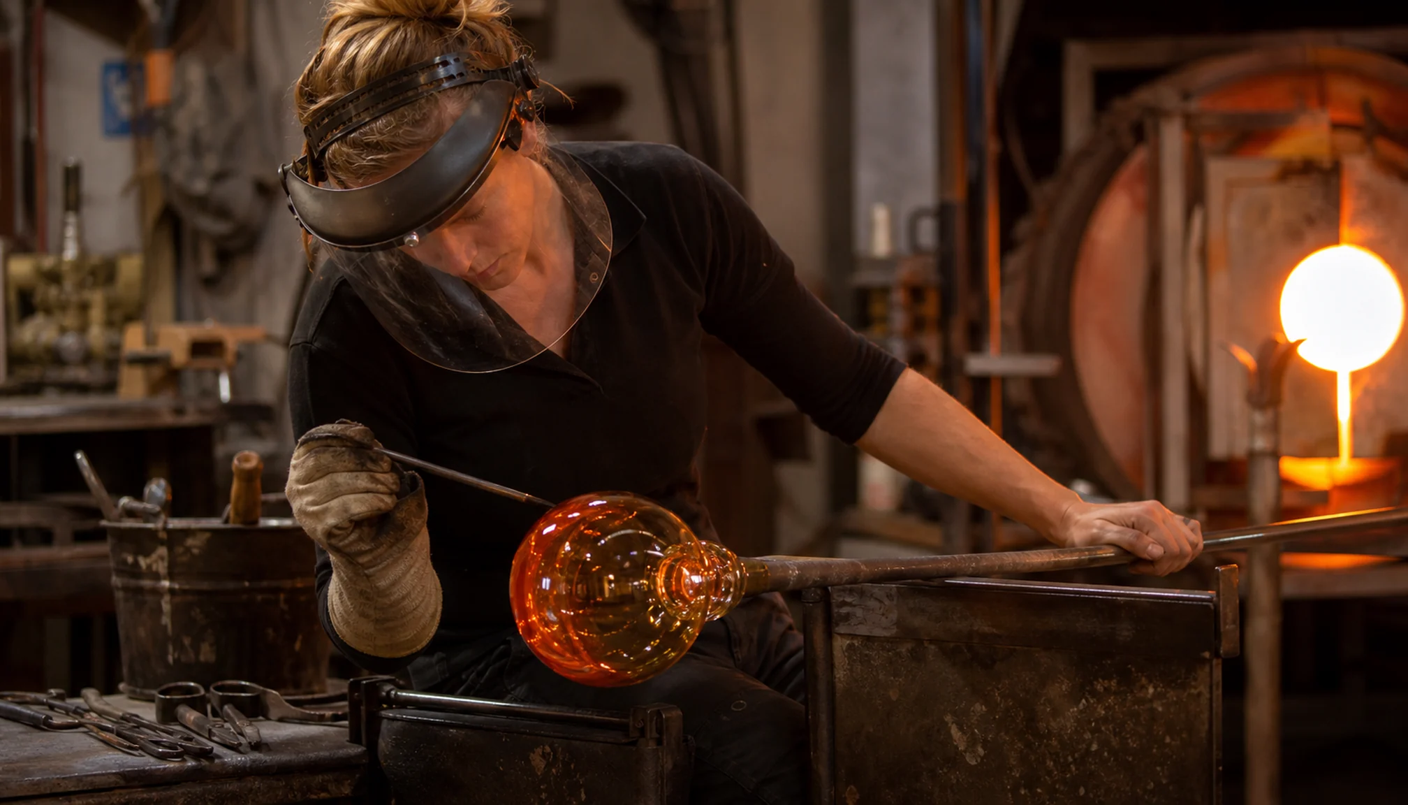 Artisane façonnant une pièce de verre en atelier